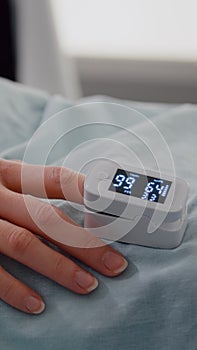 Close up of hospitalized woman with finger heart rate monitor showing pulse