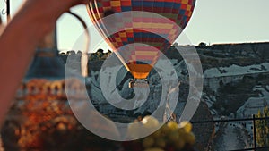 Close-Up of hot air baloon on sunrise in Cappadocia. Forefront young woman picking berries.