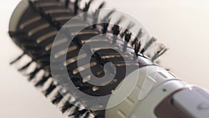 Close up of hot air rotating hair styler in female hands. Concept. Woman hands showing the work of air dryer isolated on