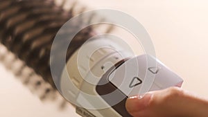 Close up of hot air rotating hair styler in female hands. Concept. Woman hands showing the work of air dryer isolated on