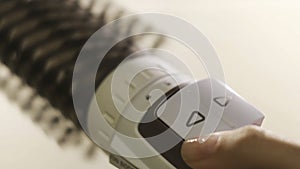 Close up of hot air rotating hair styler in female hands. Concept. Woman hands showing the work of air dryer isolated on