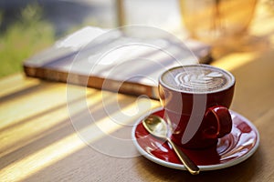 Close up hot art Latte, cappuccino Coffee in red cup on wooden table in Coffee shop blur background with bokeh image