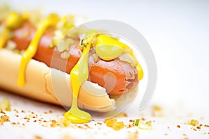close-up of a hot dog bite with mustard oozing out