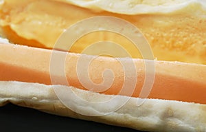 Close up of hot dog with cheese on dish