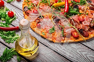 A close-up of hot margarita pizza on a rustic table background. Whole Italian pizza with vegetables and olive oil.