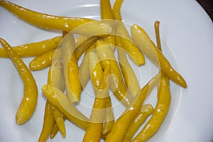 Close up of hot pickled yellow Chili Peppers served on white plate,