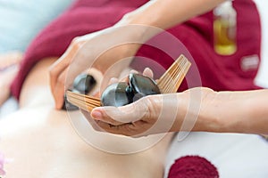 Close up hot stone lying down on skin back woman.  Asian beauty woman lying down on massage bed with traditional hot stones along