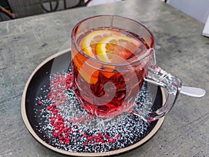 Close-up of a hot tea mug with grenadine and fruits on a table in a cafe