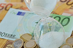 Close-up of hourglass on euro money background - Concept of countdown, deadline and time is money