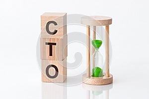 Close-up of an hourglass next to wooden blocks with the text CTO