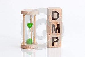 Close-up of an hourglass next to wooden blocks with the text DMP