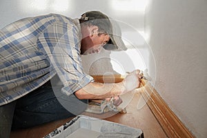 Close up of the house painter. Man, painting a wall with white paint and a paint roller or brush. Selective focus