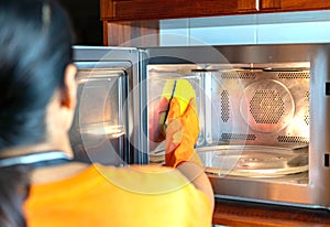 Close up housemaid cleaning microwave oven inside