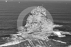 Close up of huge cliff rock one of deux jumeaux in atlantic ocean with waves in black and white