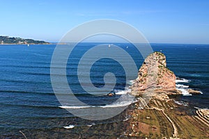 Close up of huge cliff rock one of deux jumeaux in atlantic ocean with waves in blue sky