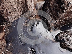 Close up human footprints. Black sand of the balinese beach with stones