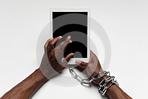 Close up of human hand using tablet with blank black screen. Tied with chain, addiction