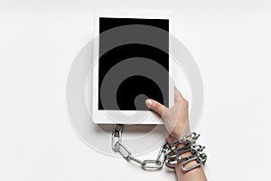 Close up of human hand using tablet with blank black screen. Tied with chain, addiction