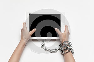 Close up of human hand using tablet with blank black screen. Tied with chain, addiction