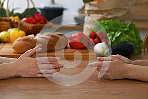 Close-up of human hands are gesticulate over a table in the kitchen. Women choosing menu or making online shopping. So