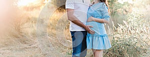 Close up of human hands holding pregnant belly, closeup happy family awaiting baby, standing on green grass, body part, young fami