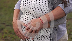 Close-up of human hands holding pregnant belly, happy family awaiting baby.