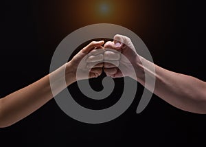 Close up of human hands making a fist bump on black background. a fist pump together after good deal