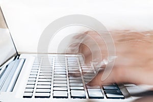 Close-up of Human Hands typing on laptop in blurred motion with