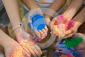 Close-up of human palms with dry paints at Holi Fest festival in city park in summer. Urban holiday. Girlfriends prepare