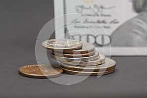 Close-up of a hundred-dollar bill and a scattered stack of dimes, selective focus. Concept :banking operations, cash settlement, c