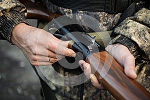 Close-up of a hunter hands loading his shotgun