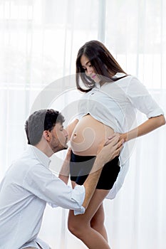 close up husband kiss pregnant woman belly - love of father to the unborn.