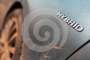 Close-up of Hybrid icon on dirty car body. Environment concept. Ecological transport