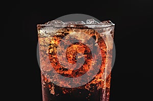 close up ice cola in glass and bubble soda on black