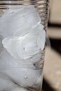 Close up of ice cubes partially melted in a clear glass