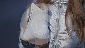 Close-up of ice skate hanging on unrecognizable brunette girl. Child doing winter sport on ice rink outdoors. Healthy