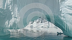 Close up iceberg arch at ocean bay aerial. Amazing environment of polar winter seascape