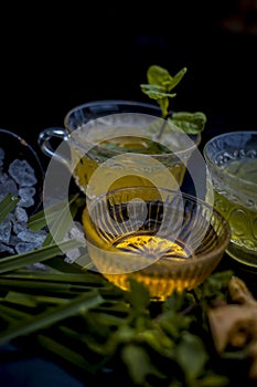 Close up of Iced lemon grass tea in a transparent cup on wooden surface with raw lemon grass green tea in a cup and sugar in a cla