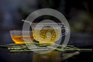 Close up of Iced lemon grass tea in a transparent cup on wooden surface with raw lemon grass green tea in a cup and sugar in a cla