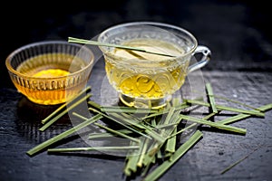 Close up of Iced lemon grass tea in a transparent cup on wooden surface with raw lemon grass green tea in a cup and sugar in a cla