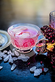 Close up of Iced tea of pomegranate and lemon on wooden surface in a transparent cup with entire ingredients with it i.e. sugar,po