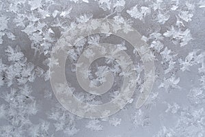 Close-up icy pattern of frozen snowflakes on window pane.