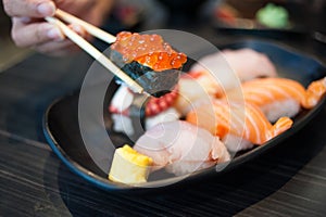 Close up of Ikura suhi in chopsticks and Variety Sushi Set