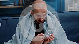 Close up of ill man looking at capsule tablets on table