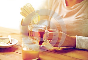 Close up of ill woman drinking tea with lemon