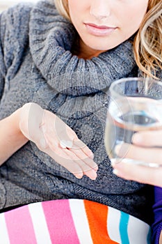 Close-up of an ill woman holding pills and water
