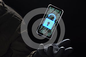 Close up illuminate unlock icon with green binary code on screen of smartphone floating above of hacker`s hand in black glove on