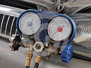 Close up image aircond gas presure meter hanging on car head lamp.