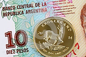 A close up image of an Argentinian 10 peso bill with a gold krugerrand