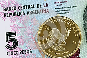 A close up image of an Argentinian 5 peso bill with a gold krugerrand